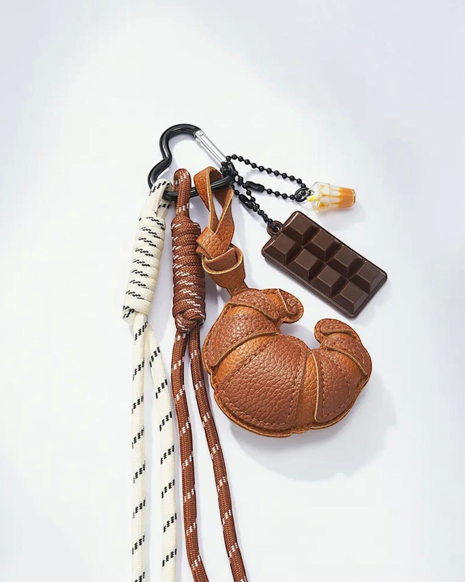 Porte-clés fantaisie avec breloques croissant en cuir marron, tablette de chocolat et boisson. Cordons tressés blanc, noir et marron.