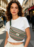 Sac banane en coton vert à motif floral porté en bandoulière par une femme dans une rue parisienne