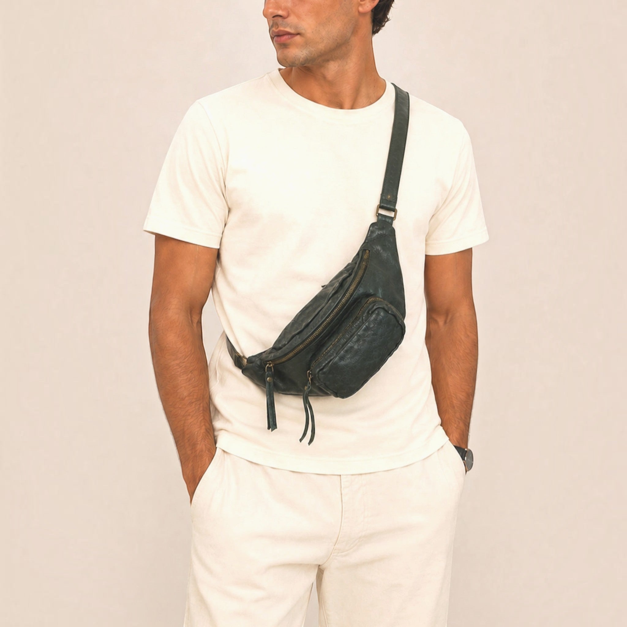 Homme portant un sac banane en cuir souple vert grainé avec fermetures zippées en bandoulière.