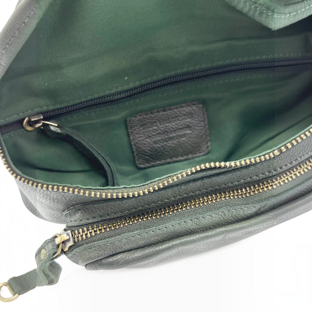 Intérieur du sac banane en cuir grainé vert profond avec doublure assortie et compartiments zippés pratiques.