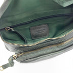 Intérieur du sac banane en cuir grainé vert profond avec doublure assortie et compartiments zippés pratiques.