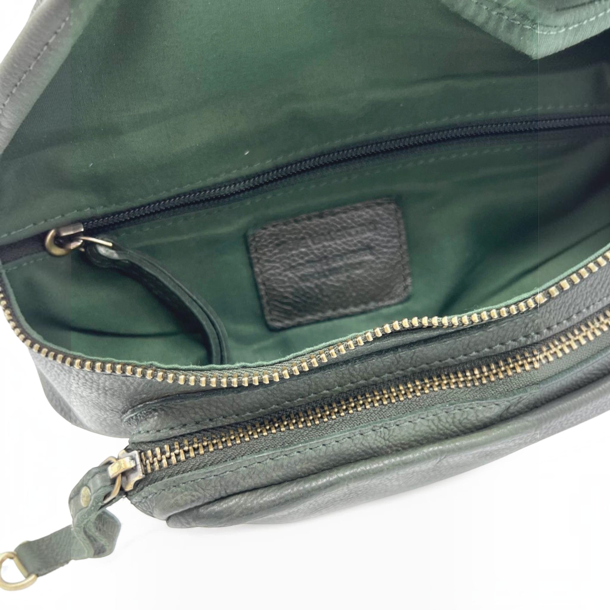 Intérieur du sac banane en cuir grainé vert profond avec doublure assortie et compartiments zippés pratiques.