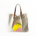 sac fourre-tout en toile crème avec imprimé citron et garniture en cuir, idéal pour la plage.