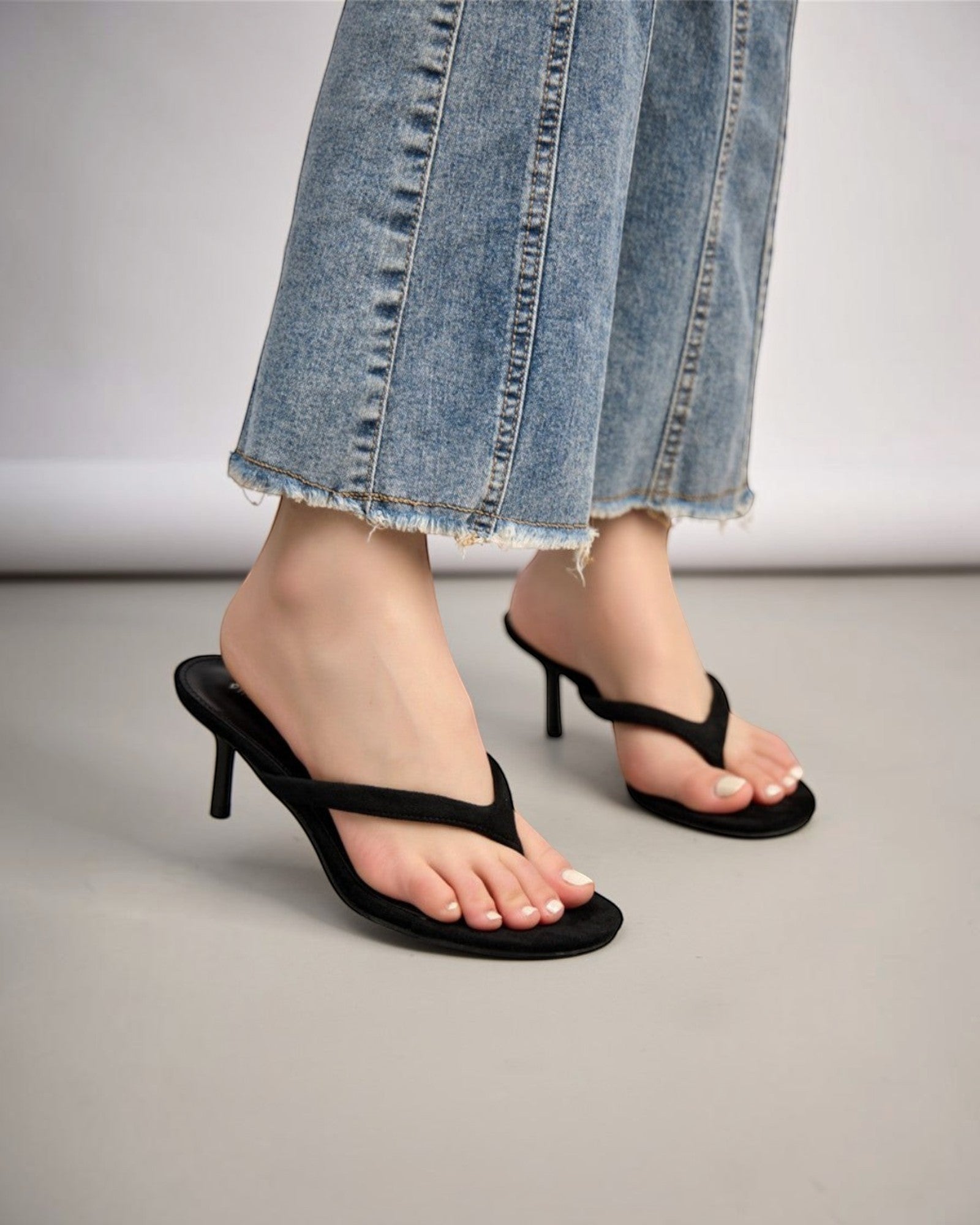 Sandales noires à talon fin et bout ouvert pour femme en daim, bride entre les orteils.