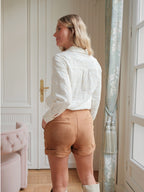Short en suédine camel  avec ourlets retroussés porté par une femme vue de dos